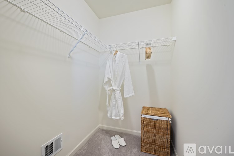 A white robe is hanging on a clothesline in a room with a basket on the floor.