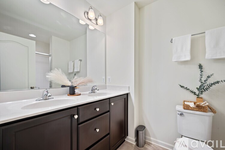 A bathroom with a white toilet and a white sink with brown drawers.