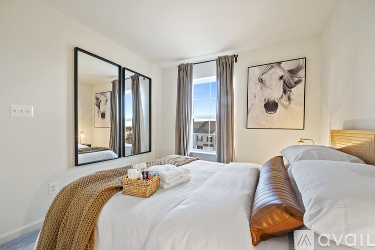 A bedroom with a large bed, a mirror, and a painting of a dog on the wall.