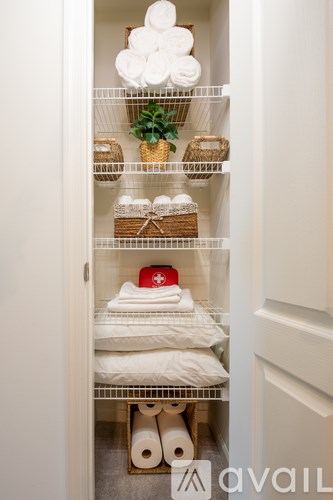 A white linen closet with towels and baskets.