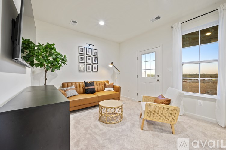 A living room with a brown sofa, a white door, and a TV mounted on the wall.