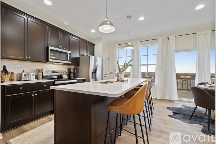 A modern kitchen with dark brown cabinets and a white island.