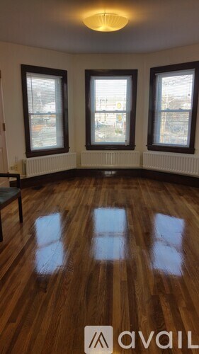 A room with wooden floors and three windows.