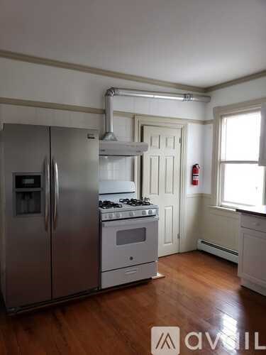 A kitchen with a stainless steel refrigerator and a white stove top oven.