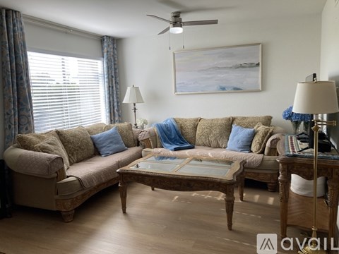 A living room with a beige sofa, a wooden coffee table, and a painting on the wall.