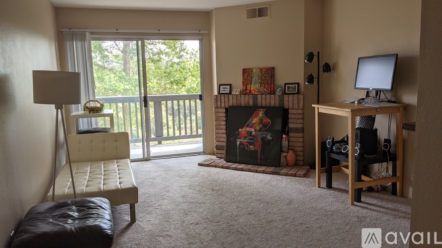 A living room with a fireplace, a chair, a desk, and a window.