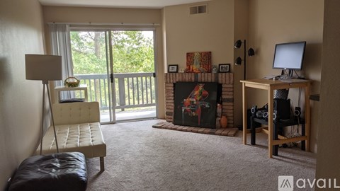 A living room with a fireplace, a chair, a desk, and a window.
