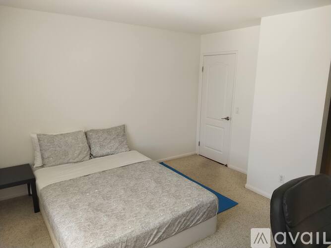 A bedroom with a bed, pillows, and a chair.