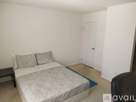 A bedroom with a bed, pillows, and a chair.
