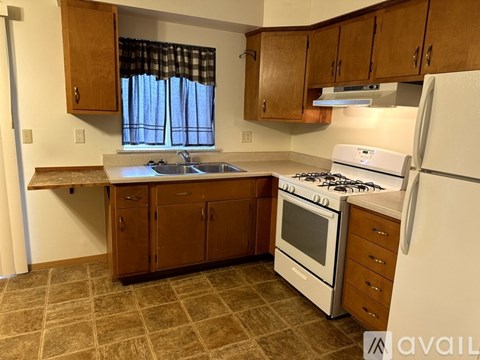 A kitchen with a white stove and wooden cabinets.