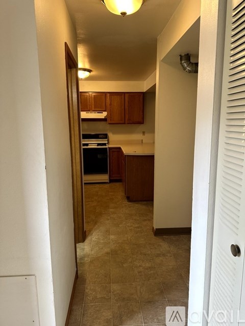 A kitchen with white walls and brown cabinets.