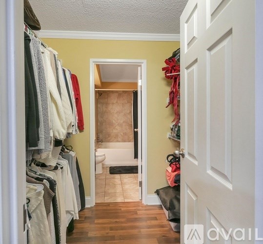 A hallway with a white door and a white bathtub in the background.