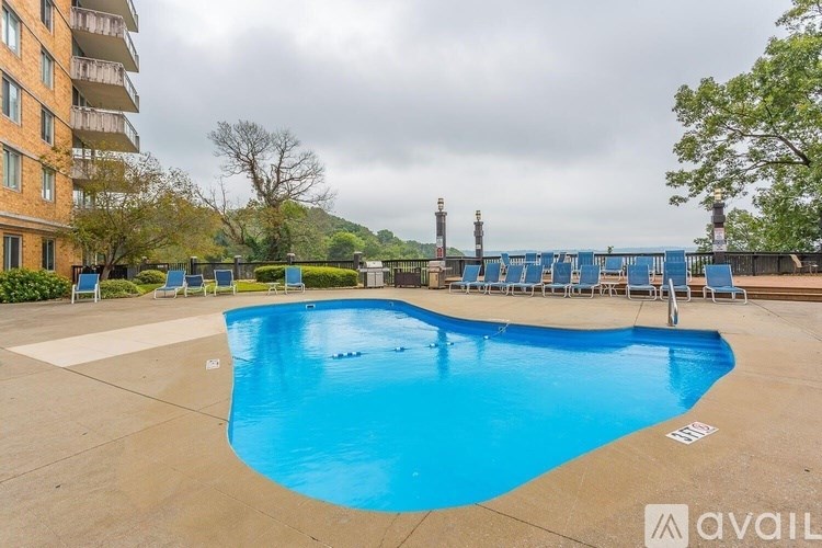 A large blue swimming pool in front of a building with chairs around it.