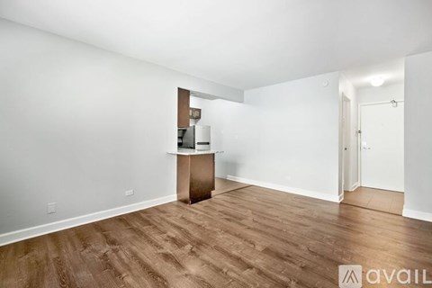 A room with wooden flooring and white walls, with a small wooden cabinet and a mirror on the wall.