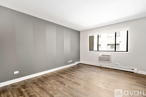 A room with wooden flooring and a window with blinds.