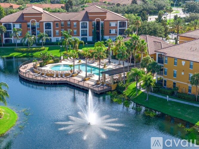 A fountain in the middle of a lake in front of a building.