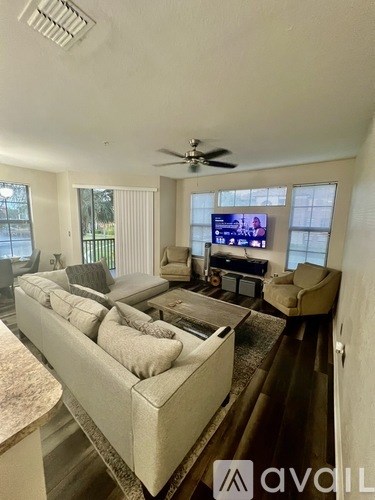 A living room with a long couch and a television on the wall.
