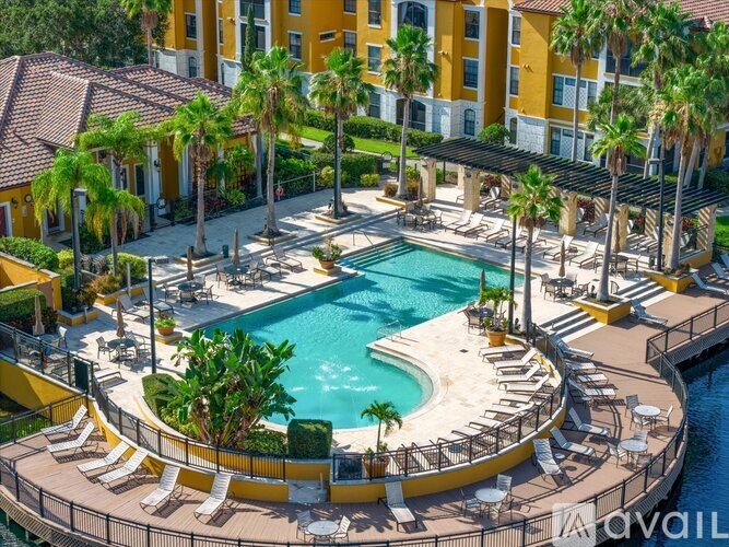 A large outdoor swimming pool surrounded by palm trees and lounge chairs.