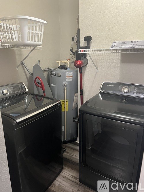 A laundry room with a washer, dryer, and ironing board.