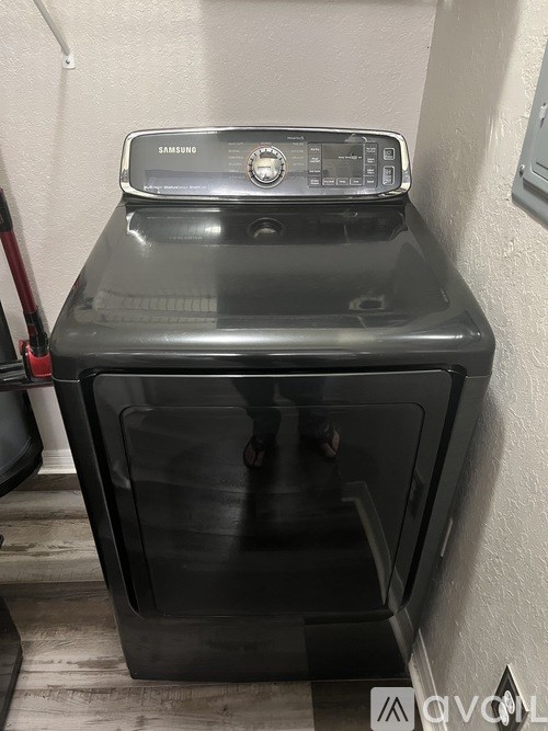 A Samsung washing machine is sitting in a small room.
