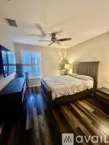 A bedroom with a bed, a ceiling fan, and a window with blinds.