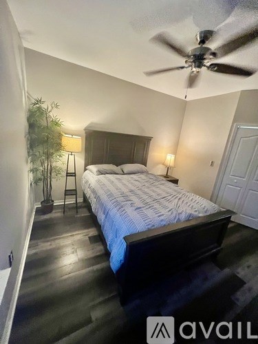 A bedroom with a bed, a ceiling fan, and a plant.