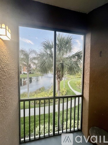 A balcony with a view of a palm tree-lined street and a building in the distance.