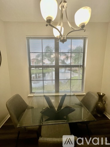 A dining room with a glass table and chairs and a chandelier.
