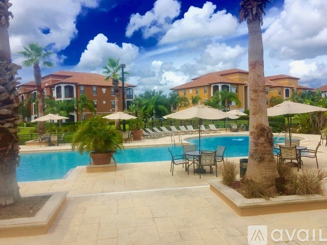 A pool surrounded by palm trees and lounge chairs.