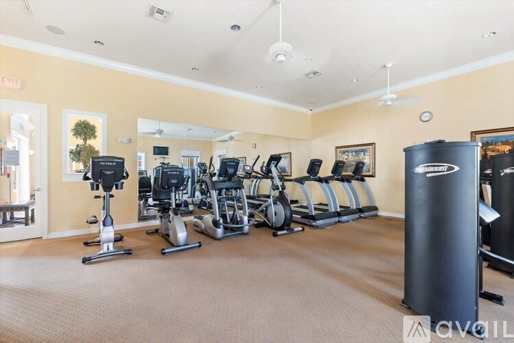 A gym with a variety of exercise equipment including treadmills, stationary bikes, and elliptical machines.