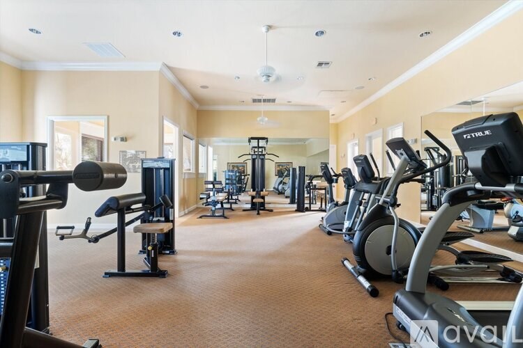 A gym with a variety of exercise equipment including treadmills, stationary bikes, and weight machines.