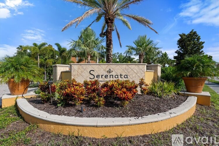 A sign that says "Serenata" is surrounded by plants and a palm tree.