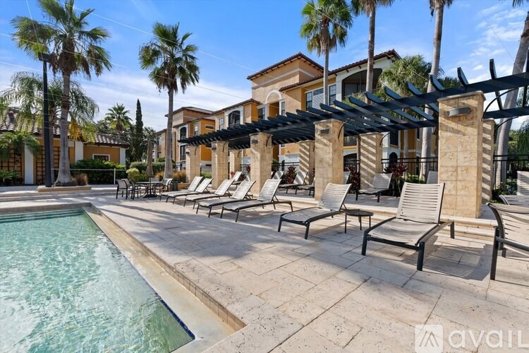 A pool area with lounge chairs and a building in the background.