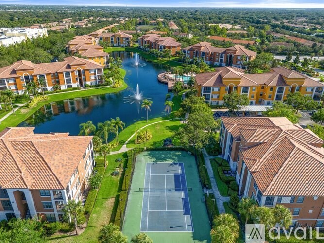 A tennis court is surrounded by apartment buildings.