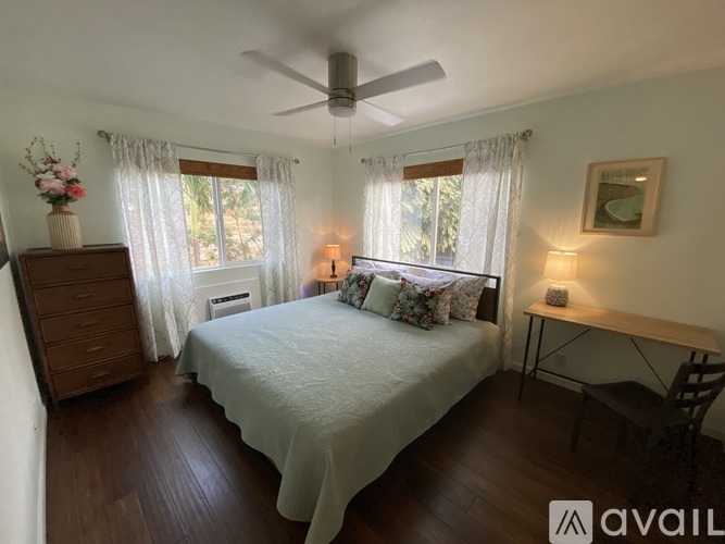 A bedroom with a bed, dresser, and window with curtains.