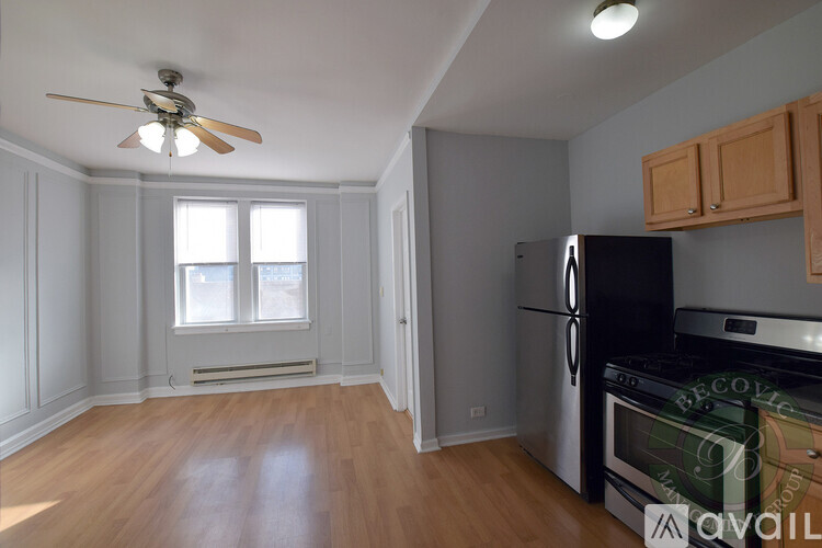 A kitchen with a black fridge and wooden floors.