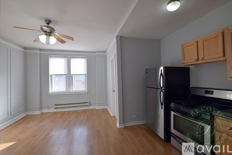 A kitchen with a black fridge and wooden floors.