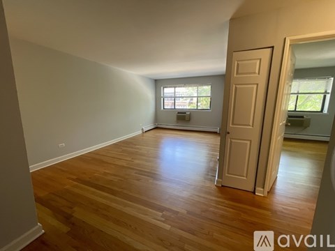A room with wooden floors and a door leading to another room.