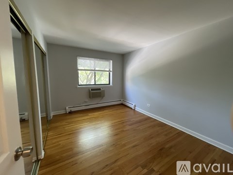 A room with wooden flooring and a window with blinds.