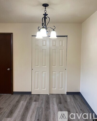 A room with a white door and a chandelier hanging from the ceiling.
