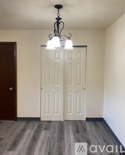A room with a white door and a chandelier hanging from the ceiling.