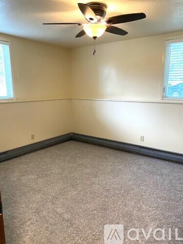 A room with a ceiling fan and carpeted floor.