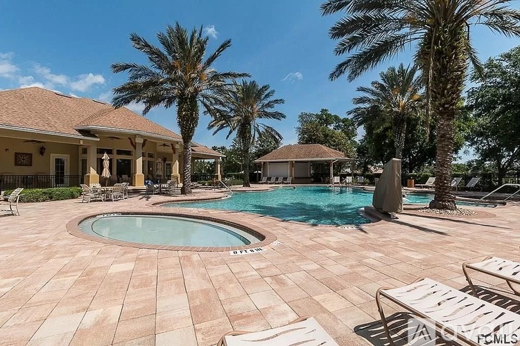 A pool surrounded by palm trees and lounge chairs.