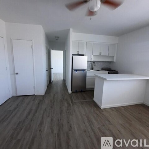 A kitchen with white cabinets and a refrigerator.