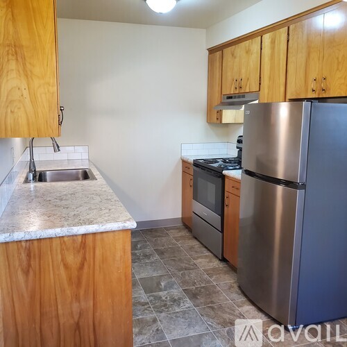 A kitchen with wooden cabinets and a stainless steel refrigerator.