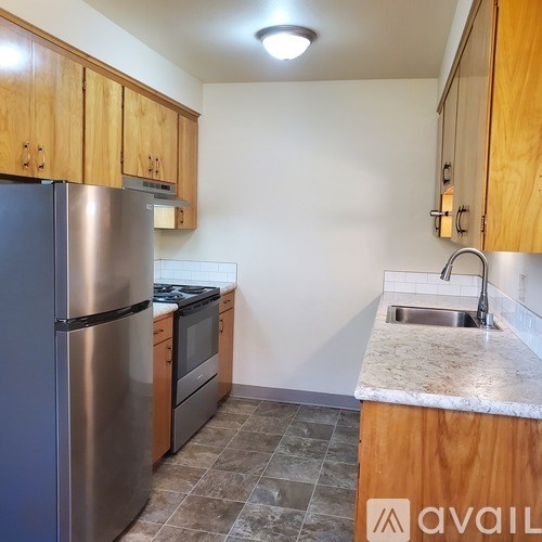 A kitchen with wooden cabinets and a stainless steel refrigerator.