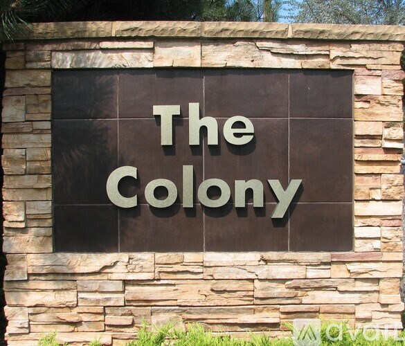 A sign that reads "The Colony" is mounted on a stone wall.