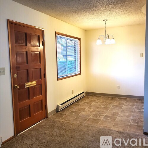 A kitchen with a refrigerator, cabinets, and a window.