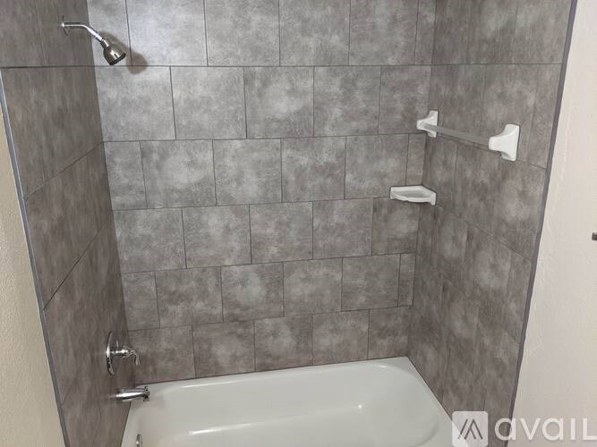 A bathroom with a shower and a white tub.