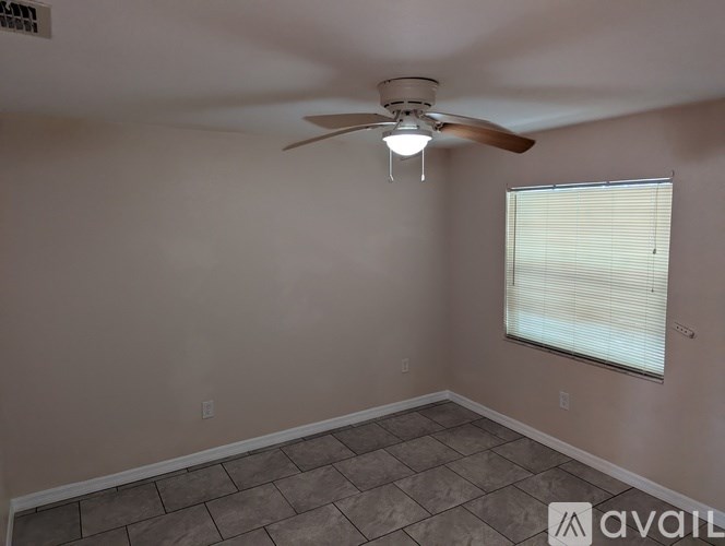 A room with a ceiling fan and a window with blinds.